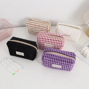 Set of five colorful corduroy makeup bags and pencil cases in a tidy desktop arrangement