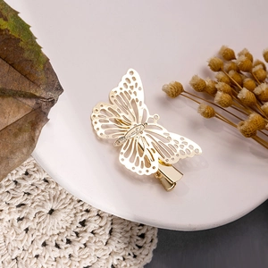 Vue détaillée d'une pince à cheveux papillon dorée ajourée sur une assiette blanche