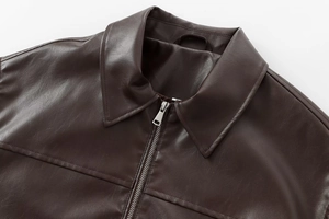 Detail of dark brown faux leather bomber jacket showing collar and metal zipper