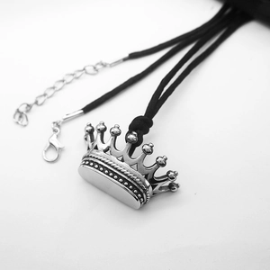 Detailed shot of silver crown pendant on black woven cord with adjustable lobster clasp