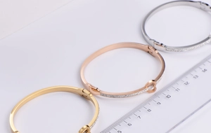 Detailed view of heart-shaped bangles in three colors with rhinestones and measurement ruler