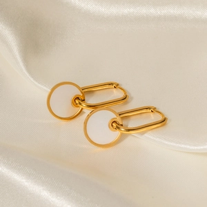 Detailed macro shot of 18K gold earrings with white mother of pearl round pendants