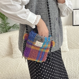 Close-up of fluffy plaid crossbody bag with metal snap button and woven rope strap