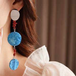 Detail of long tassel earrings with red beads and blue marble resin on a model