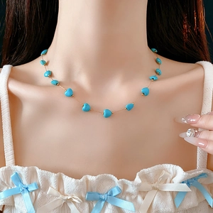 Detail showing a bohemian gold necklace with blue heart turquoise beads on a model's neck