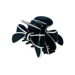 Detail of a chic black and white bow-shaped hair claw clip with glossy resin finish