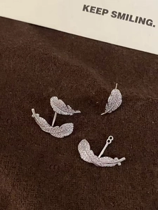 Detail of silver feather stud earrings with micro-paved zircons on brown velvet