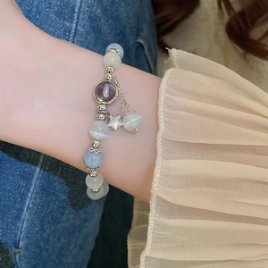 Elegant beaded bracelet with star pendant and zircon, worn on wrist over denim fabric