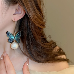 Close-up of elegant long earrings with teal acrylic butterfly and white cotton pearl