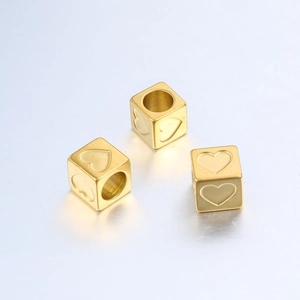 Detailed macro view of three 6mm golden stainless steel heart engraved cube beads