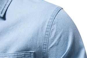 Close-up of double-needle stitching and fabric texture on light blue denim shirt