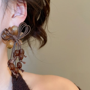 Detail of amber resin bow earrings with woven tassels and beads in vintage style