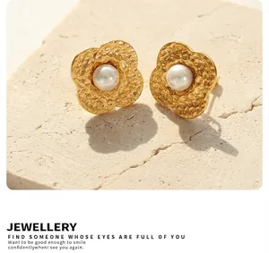 Detailed macro view of gold-plated flower stud earrings with hammered petals and pearl centers