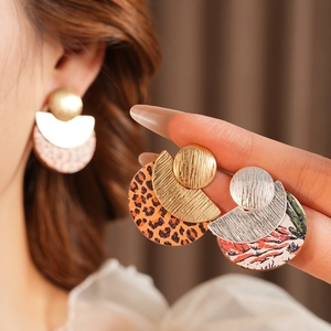 Detail view of round leopard print and tiger stripe wooden drop earrings on a model