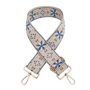 Detail of blue and beige embroidered folk purse strap with gold metal hooks and buckle