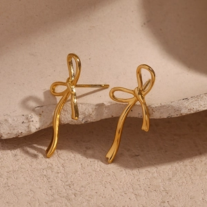 Elegant 18K gold plated stainless steel bow stud earrings on a textured stone surface