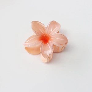 Detail of peach orange plumeria hair claw clip with glossy resin finish and 8cm size