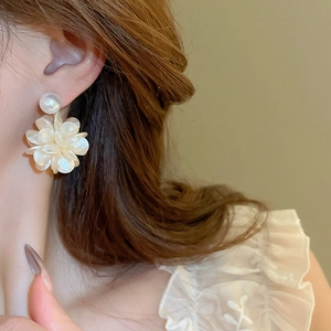 Nahaufnahme einer Dame mit eleganten weißen Kamelienblüten-Ohrringen mit Perleffekt