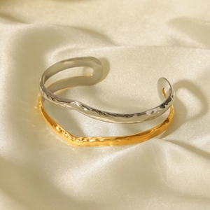 Two-tone hammered open bangle in gold and silver finish with wavy texture on silk background