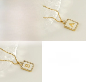 Detailed macro view of square alphabet necklace with natural shell inlay and crystals