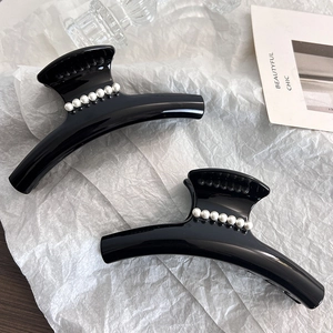 Close-up of two large black hair claw clips with elegant white pearl details