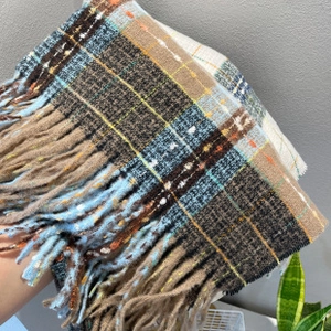 Close-up of soft plaid mohair scarf with tassels in blue, brown, and beige tones