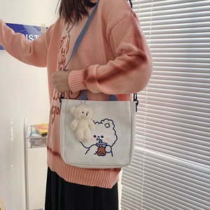 Nahaufnahme der weißen Segeltuchtasche mit Comic-Illustration und Plüschbär-Anhänger
