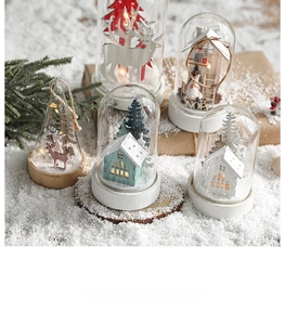 Détail de dôme en verre de Noël nordique avec maison en bois et scène de rennes LED