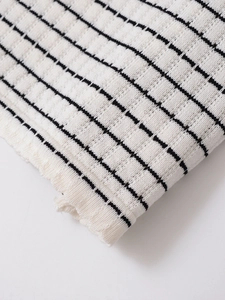 Vue détaillée du tricot côtelé texturé blanc avec de fines rayures noires horizontales
