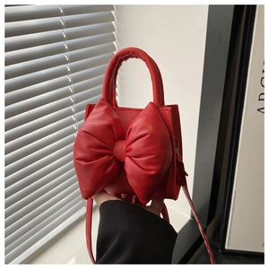 Detail shot of a red PU leather handbag with a large bow decoration and smooth finish