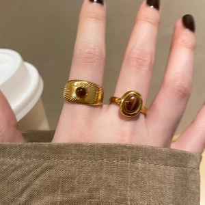 Close-up of vintage gold rings set with brown oval gemstones on model's hand