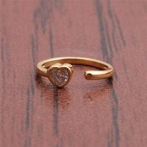Macro view of gold minimalist heart ring with clear crystal stone on wood