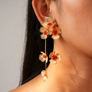 Vue macro de boucles d'oreilles fleurs dorées avec étamines rouges et détails pompons