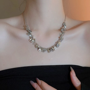 Detail of silver waterdrop sequin fringe necklace worn on neck highlighting clavicle area
