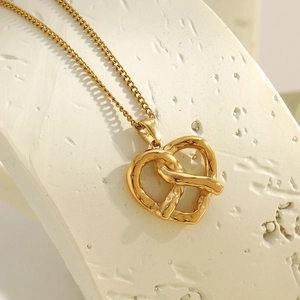 Macro shot of 18K gold plated stainless steel twisted heart pendant with soft lighting
