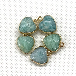 Detailed view of heart-shaped malachite stone pendants with golden metal edges for jewelry