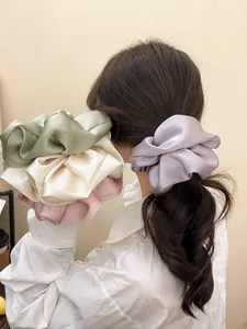 Macro shot of oversized satin scrunchies in pastel colors with rich glossy folds