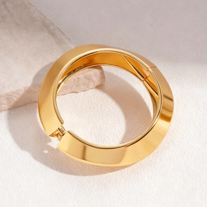 Detailed shot of a wide gold chunky cuff bracelet featuring geometric faceted metal textures