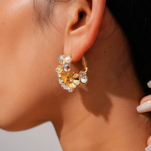 Macro view of C-shaped flower earrings with colorful rhinestones and white pearls on model