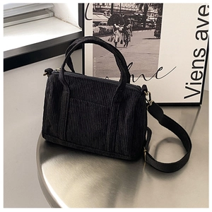 Detailed texture of black corduroy Boston bag featuring top handles and adjustable strap
