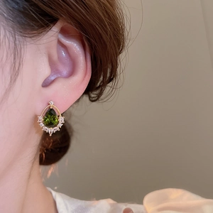 Nahaufnahme von Vintage 18k vergoldeten Tropfenohrringen mit grünem Kristall am Model