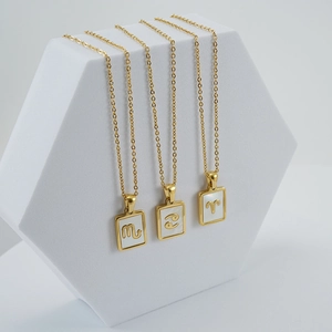 Three 18K gold plated stainless steel necklaces with shell zodiac pendants on a white stand