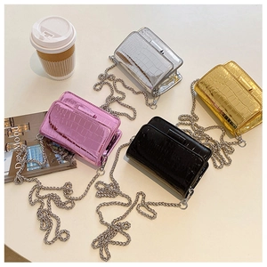 Flat lay of mini patent faux leather crossbody bags in four metallic colors with chain straps