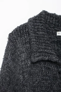 Gros plan sur le col d'un cardigan en maille gris foncé avec une petite étiquette blanche