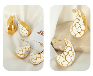 Vue détaillée des boucles d'oreilles en émail blanc avec craquelures dorées style français