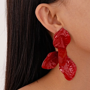 Close-up of stylish glossy red floral petal earrings worn by a model in a side view profile