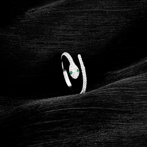 Macro detail of silver snake ring with white pavé stones and green gemstone eyes