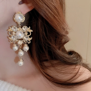 Détail de boucles d'oreilles baroques à pampilles en perles et fleurs en cristal