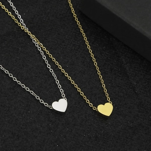 Colliers avec pendentifs en forme de cœur en or et argent sur surface noire texturée