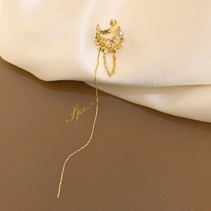 Détail d'un ear cuff doré orné de strass, de perles et d'une longue chaîne à franges